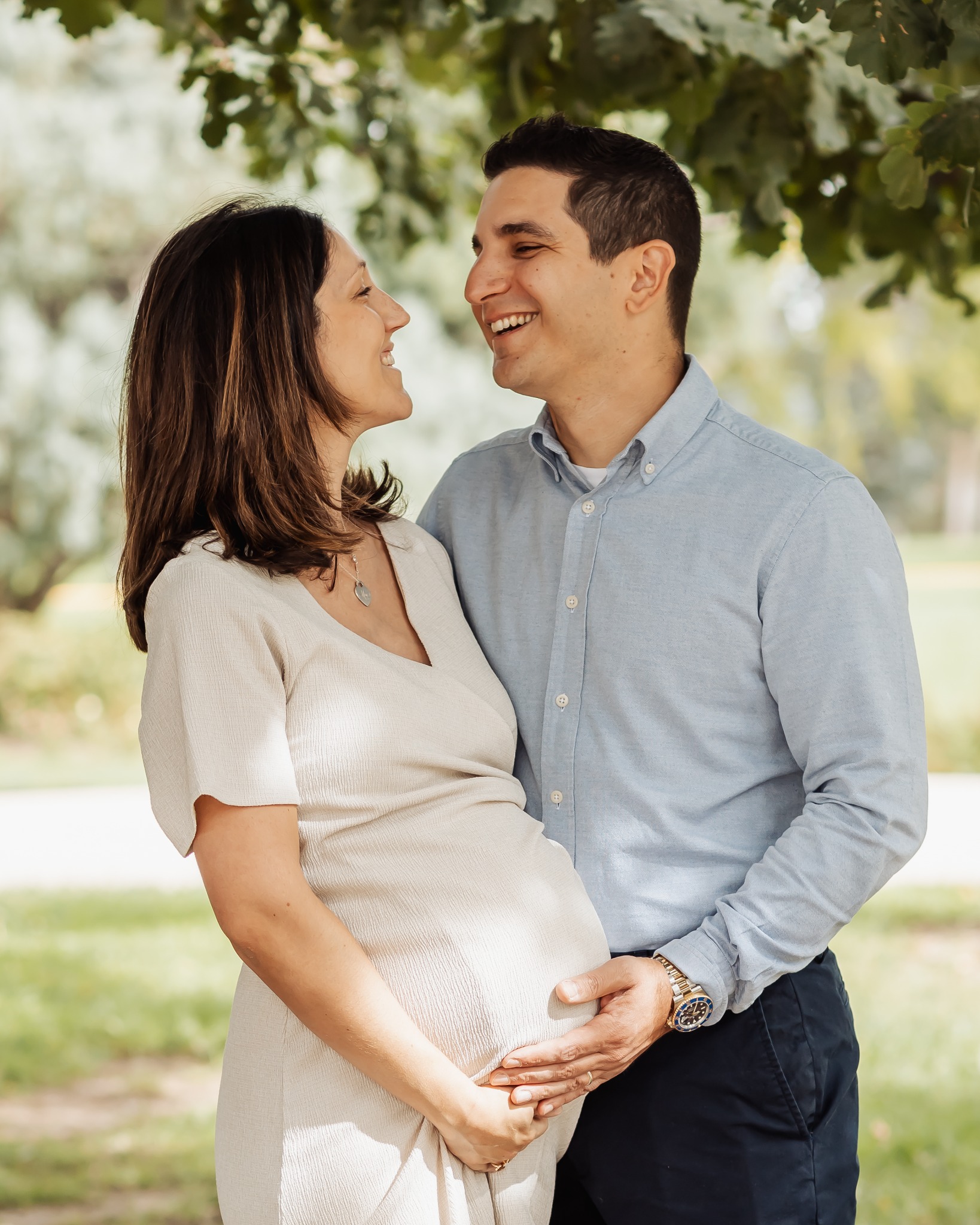 Emily and Steven smiling together while holding the baby bump