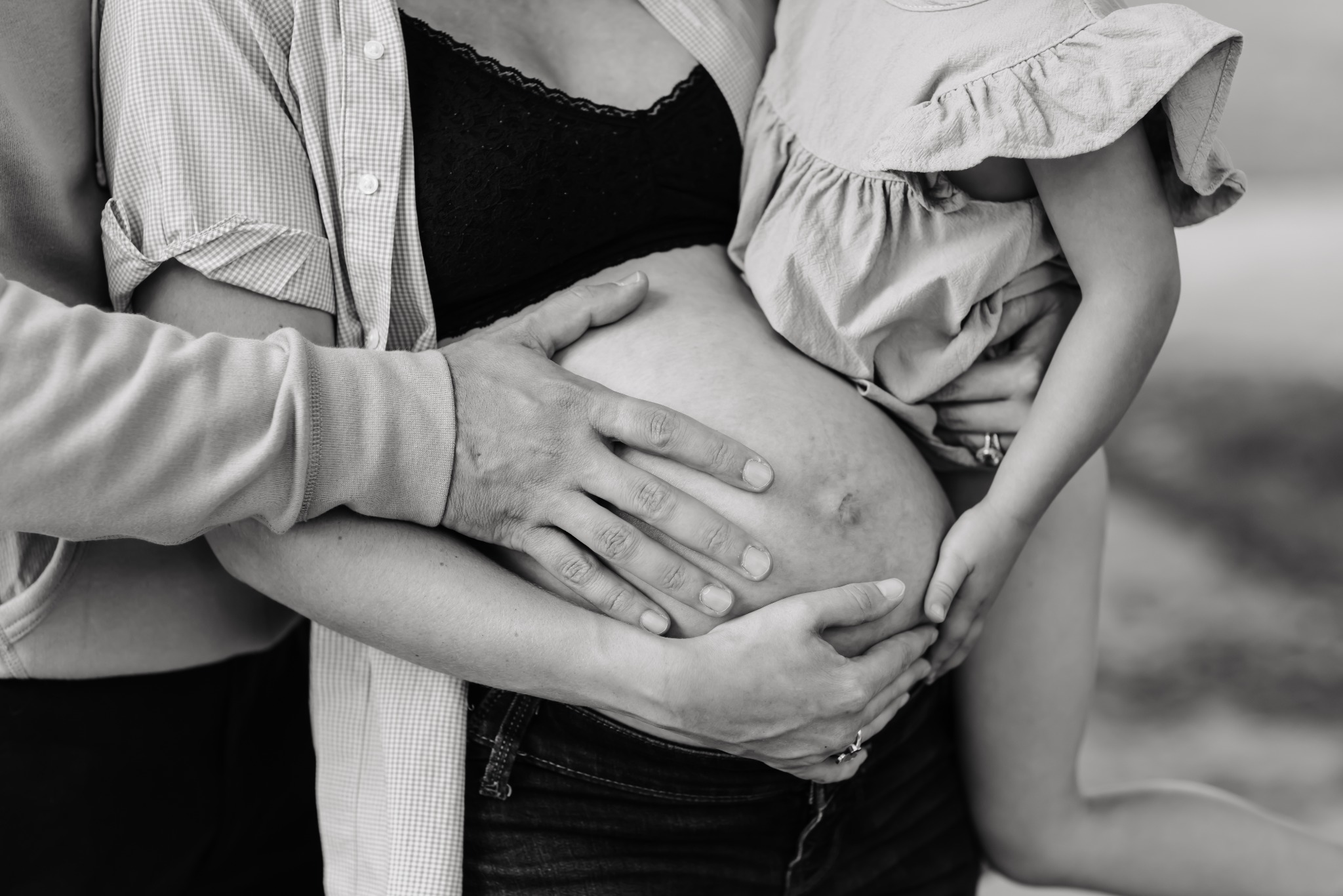 Family hands resting on Emily’s baby bump